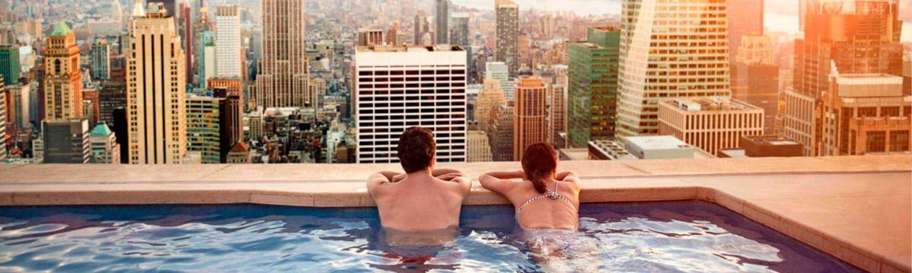 Una pareja mirando al skyline de Nueva York desde una piscina
