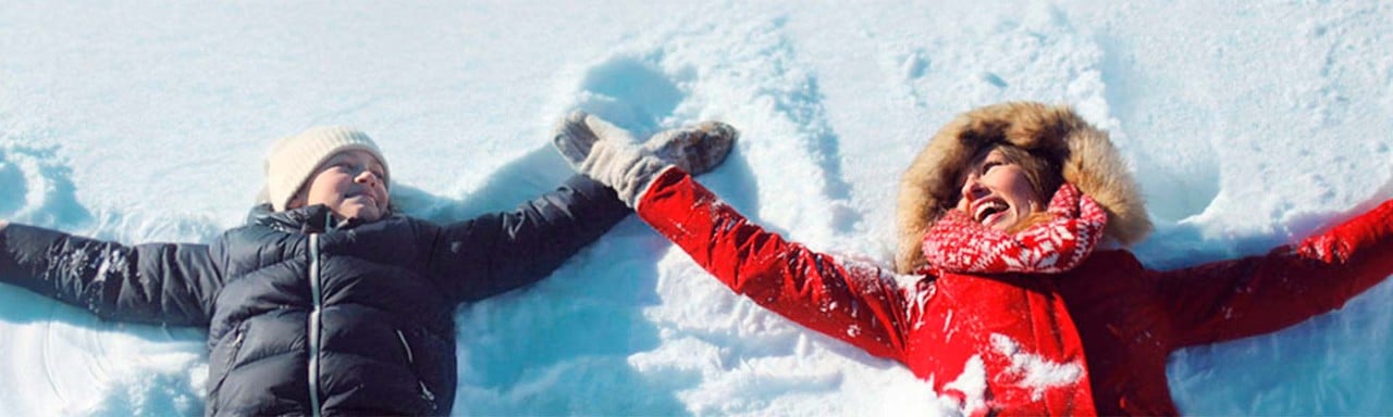 Madre e hijo tumbados en la nieve
