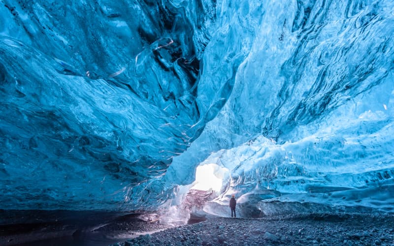 mochilero caminando por la cueva de hielo del glaciar vatnajökull en Islandia