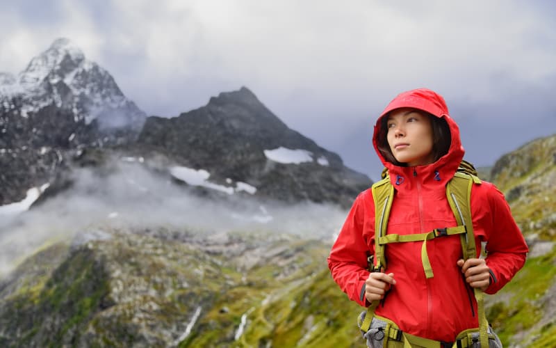 mochilera caminando por los alpes con chubasquero en suiza